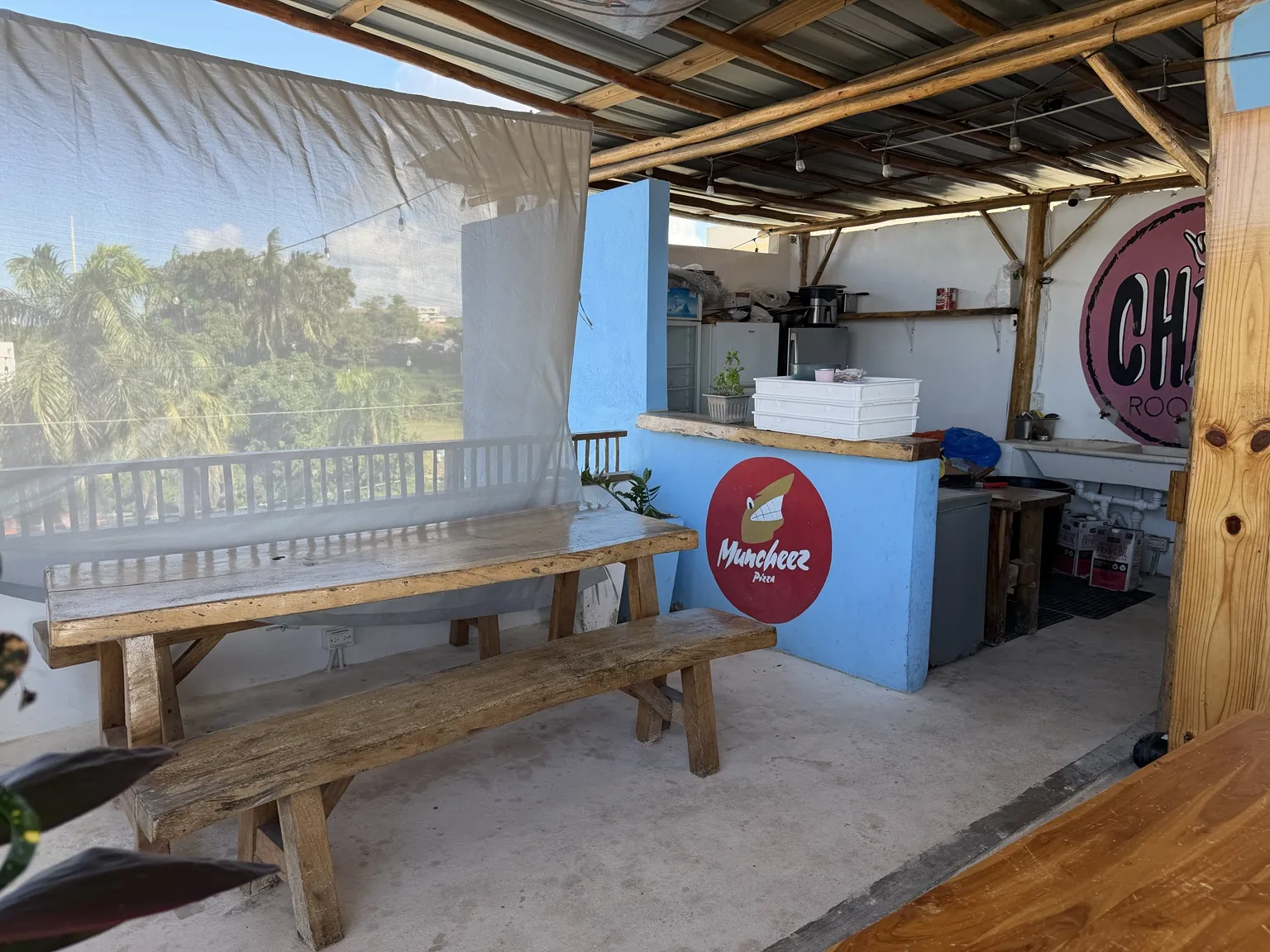 A real photo of Chill Rooftop's covered seating area and bright blue kitchen counter