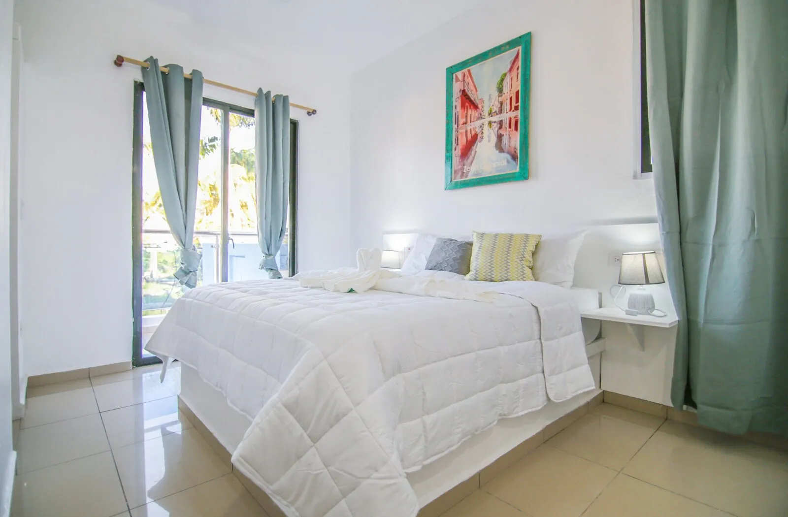 Chill guest room with white bedding, turquoise curtains and balcony doors